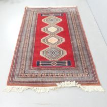 A handmade red ground Uzbek Bokhara rug. 205x130cm.