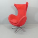 A red upholstered egg chair in the manner of Arne Jacobsen for Fritz Hansen.