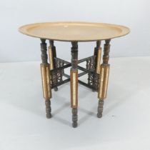 An eastern brass circular tray-top table, on folding based with inlaid mother-of-pearl and carved