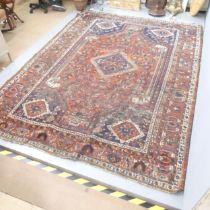 A red-ground Quashqai rug. 305x227cm. Heavily worn in some places. Fringes have been trimmed.