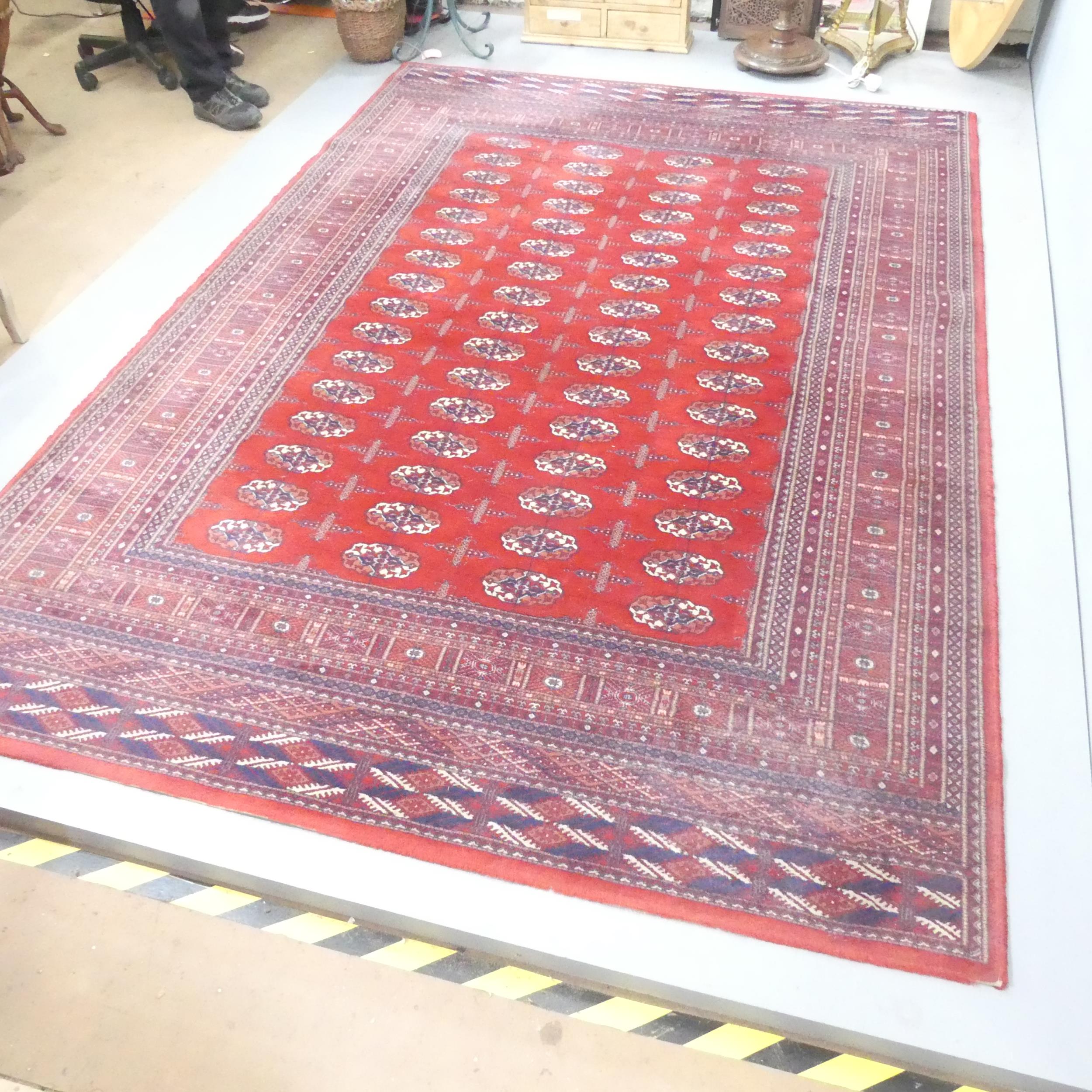 A red-ground machine made Tekke design carpet. 300x200cm.