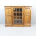 An early 20th century oak break-front three-door bookcase, with applied carved decoration.