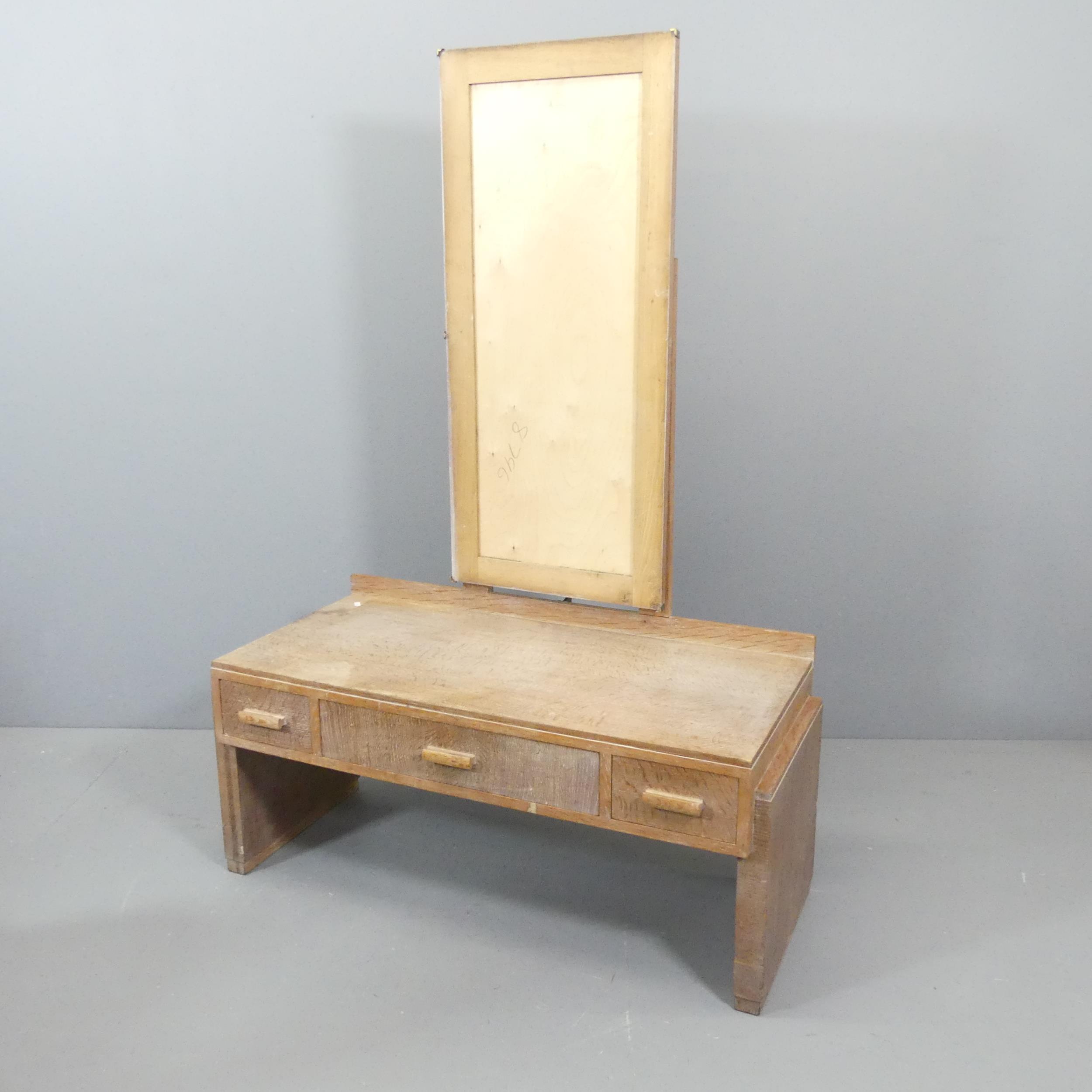 HEALS - A limed oak dressing table, with raised back, three drawers and maker's label. 107x154x49cm.