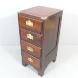 An oak narrow campaign style chest of four drawers, with inset tooled and embossed red leather