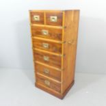 A teak and walnut veneered campaign style narrow chest of seven drawers. 47x108x38cm.