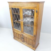 A modern oak bookcase, with carved decoration, two lattice-glazed doors and cupboards under.
