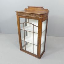 An early 20th century mahogany display cabinet, with carved decoration and lattice glazed door.