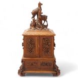 An ornate 19th century Black Forest table cabinet, the lid surmounted a carved wood group of deer, 2