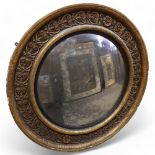 A large Georgian convex mirror, with gilded relief carved wood and gesso surround, original oxidised