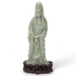 A Chinese carved green jade figure of Guan Yin on carved hardwood stand, overall height 32cm,