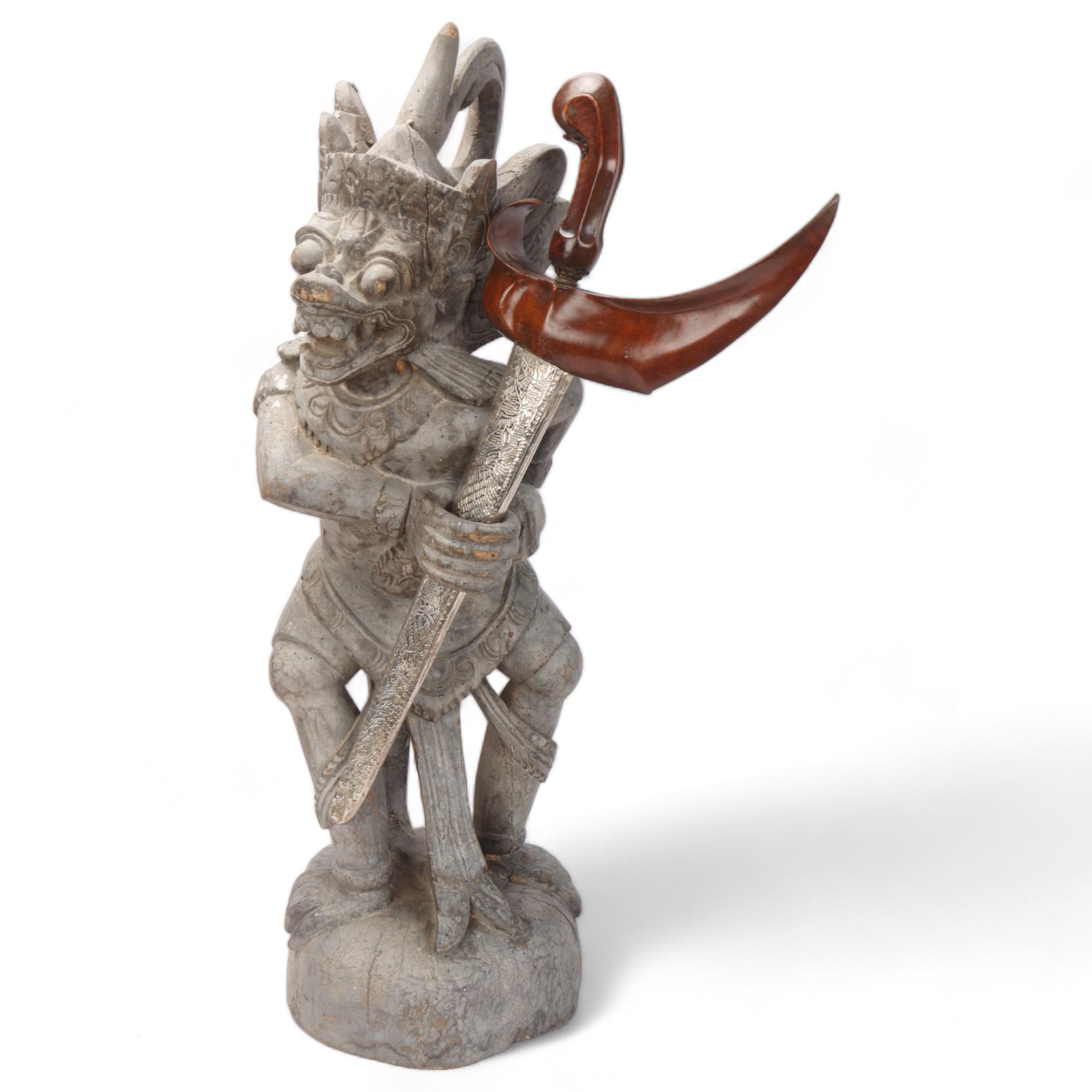 A Malayan carved wood grotesque figure Kris stand, together with a Kris dagger in white metal