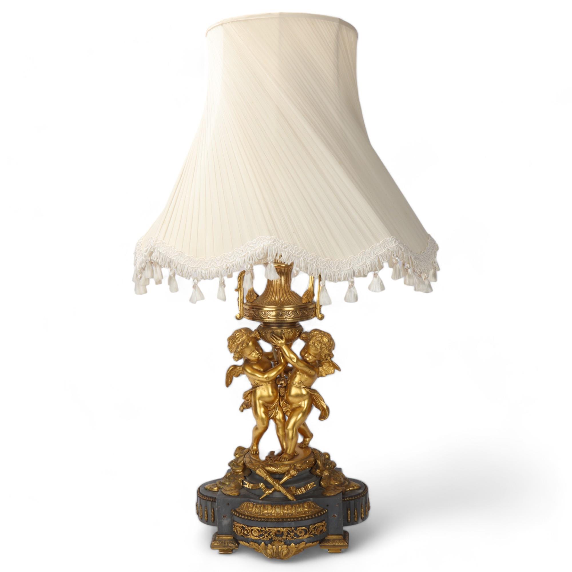 An ornate French gilt-bronze table lamp, supported by 2 cherubs, probably late 19th century, on