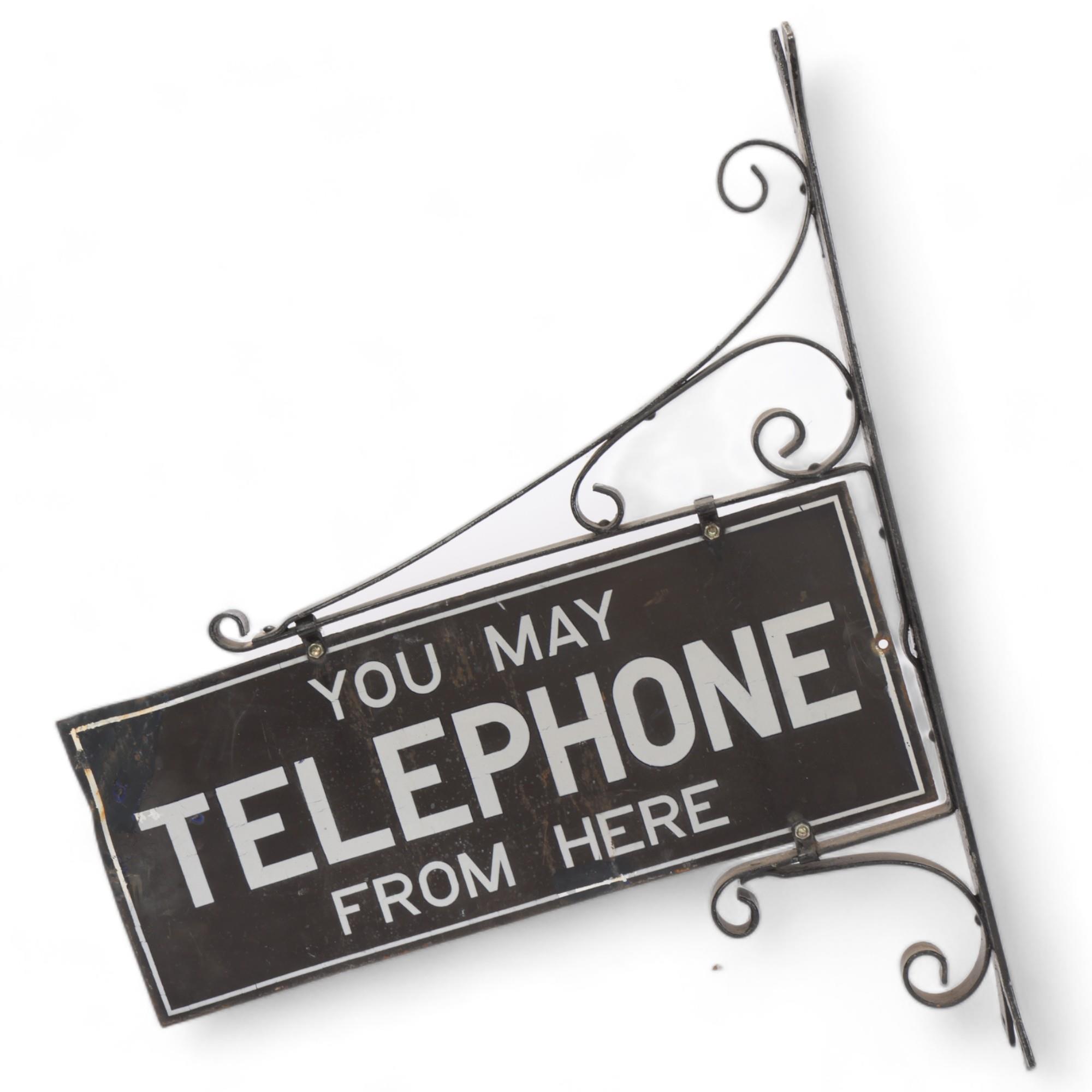 A Vintage enamel sign "You May Telephone From Here", double-sided in wrought-iron wall mounted