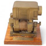 A bronze sculpture of an engine block, presented to an engineer on his retirement, unsigned, on wood