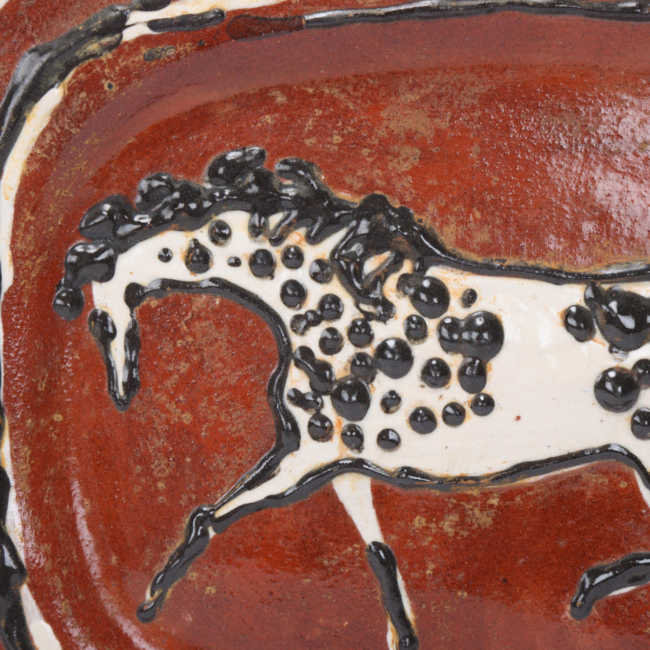 A mid 20th century earthenware charger, with slip glaze horse decoration, wire frame for wall- - Image 2 of 3