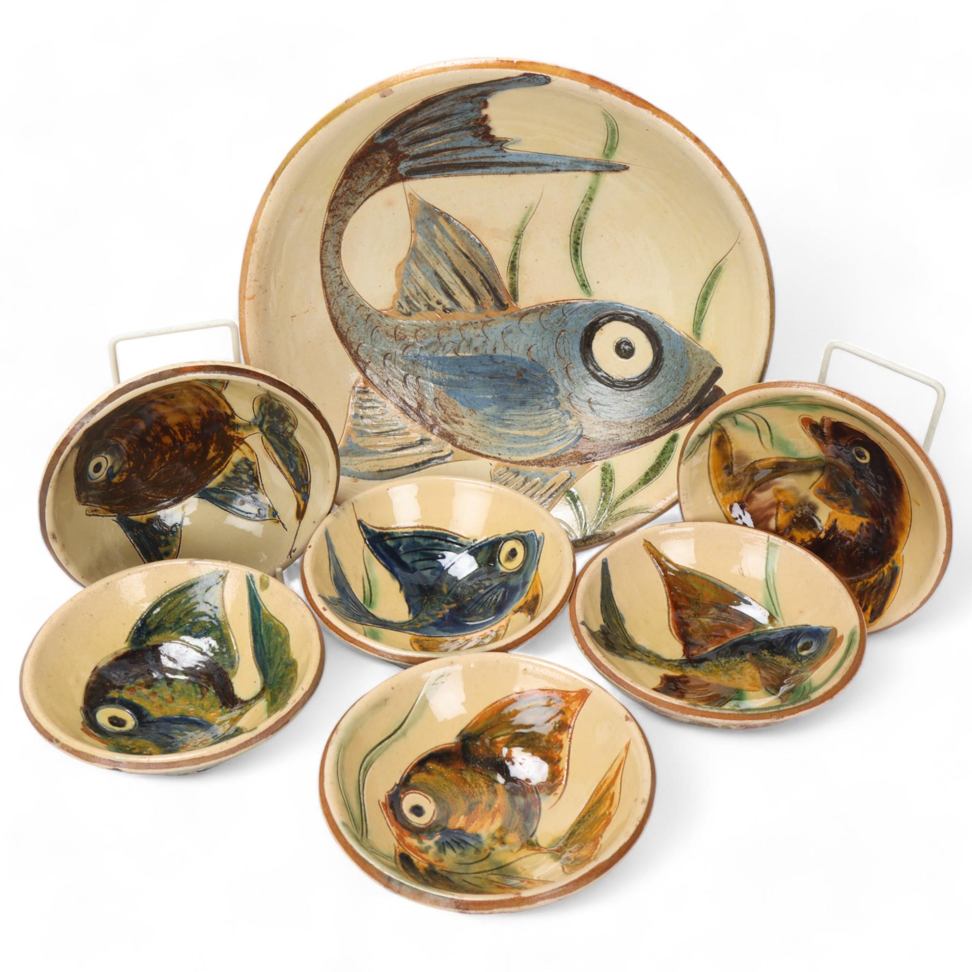A large earthenware bowl with slipware fish decoration, together with six smaller bowls by the
