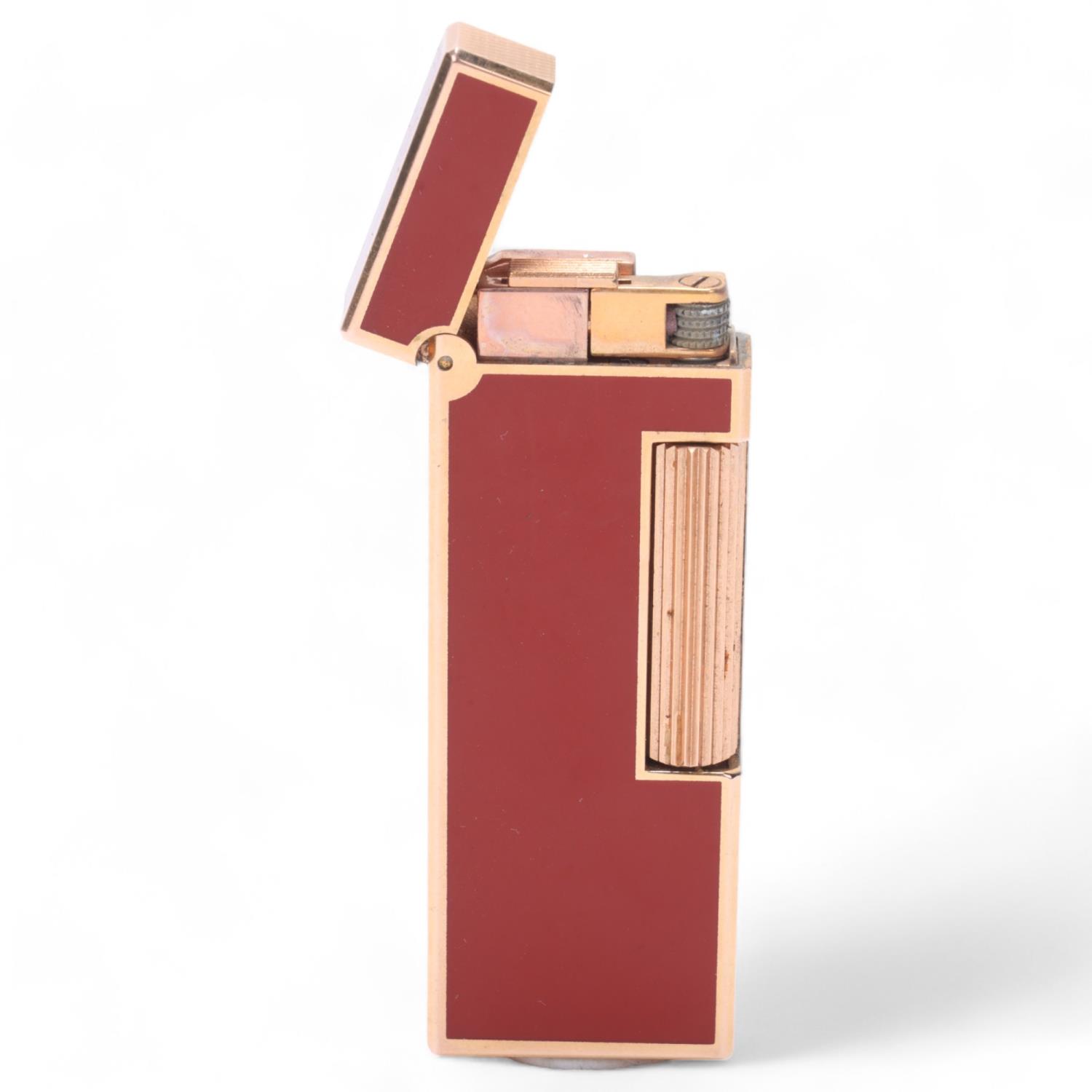 A Dunhill slimline Rollagas lighter, gold plated with red lacquer body, makers marks to base,