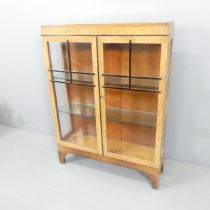 An Art Deco maple veneered display cabinet, with two glazed doors and ebonised fretwork.