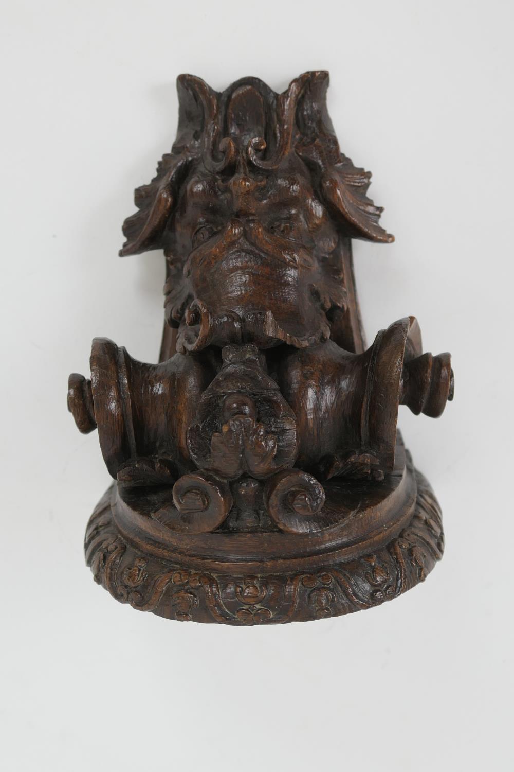 Late 17th Century carved oak bracket, carved with a grotesque mask and paper scroll, 22cm x 16.