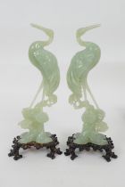 Pair of Chinese pale celadon jade ornaments, carved as cranes standing on a rock, with carved wooden