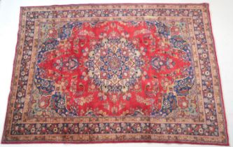 Tabriz red ground woollen carpet, centred with a blue, red and fawn pendant medallion bordered