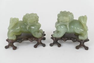 Pair of Chinese carved celadon green jade Kylins, 20th Century, on carved wooden stands, 11.5cm x