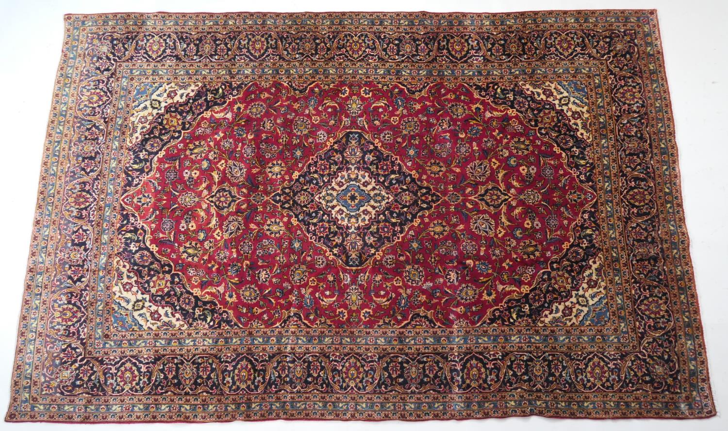 Kashan deep red ground woollen carpet, centred with a blue and fawn medallion, the field dispersed