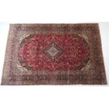 Kashan deep red ground woollen carpet, centred with a blue and fawn medallion, the field dispersed