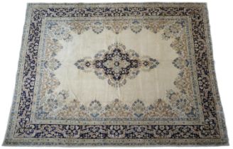 Kirman fawn ground woollen carpet, centred with a pink blue and pink foliate medallion, bordered