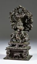 An Indian Cast Bronze Figure of Krishna, 19th/20th Century, playing a flute, against a bull, beneath
