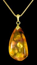 An Amber Pendant and Chain, reconstituted amber pendant, 45mm x 25mm set in yellow coloured metal