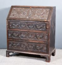 A Late 18th Century Carved Oak Bureau, the slope carved with leaf scroll ornament, enclosing central