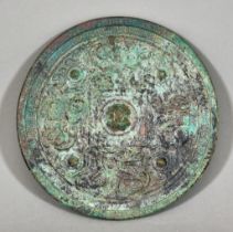 A Chinese Patinated Bronze Circular Mirror of Archaic Form, the plain silvered face with green