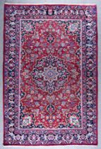 An Early 20th Century Tabriz Carpet woven in colours of madder, navy blue and ivory, with a bold