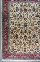 An Antique Tabriz Carpet, woven in colours of ivory, navy blue and wine, the field filled with