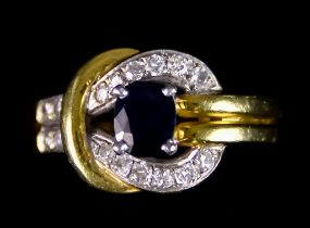 An 18ct Gold Sapphire and Diamond Buckle Ring, set with a synthetic sapphire, approximately .75ct,