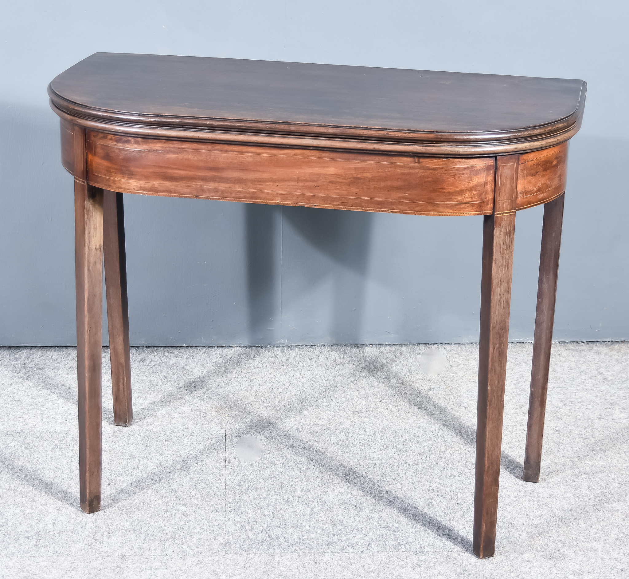 A George III Mahogany Card Table with moulded edge to the baize lined folding top, plain frieze,