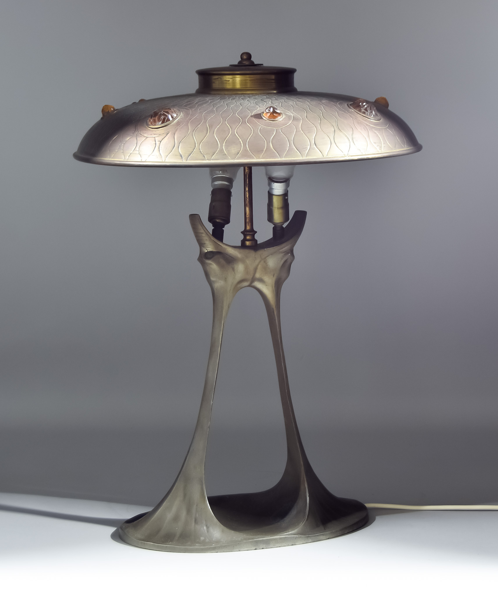 A Bronzed Pewter Table Lamp of Art Nouveau Design with pressed metal, bronzed circular shade, for