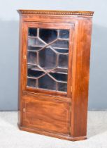 A George III Corner Cupboard with moulded cornice and dentil frieze, fitted two shelves enclosed