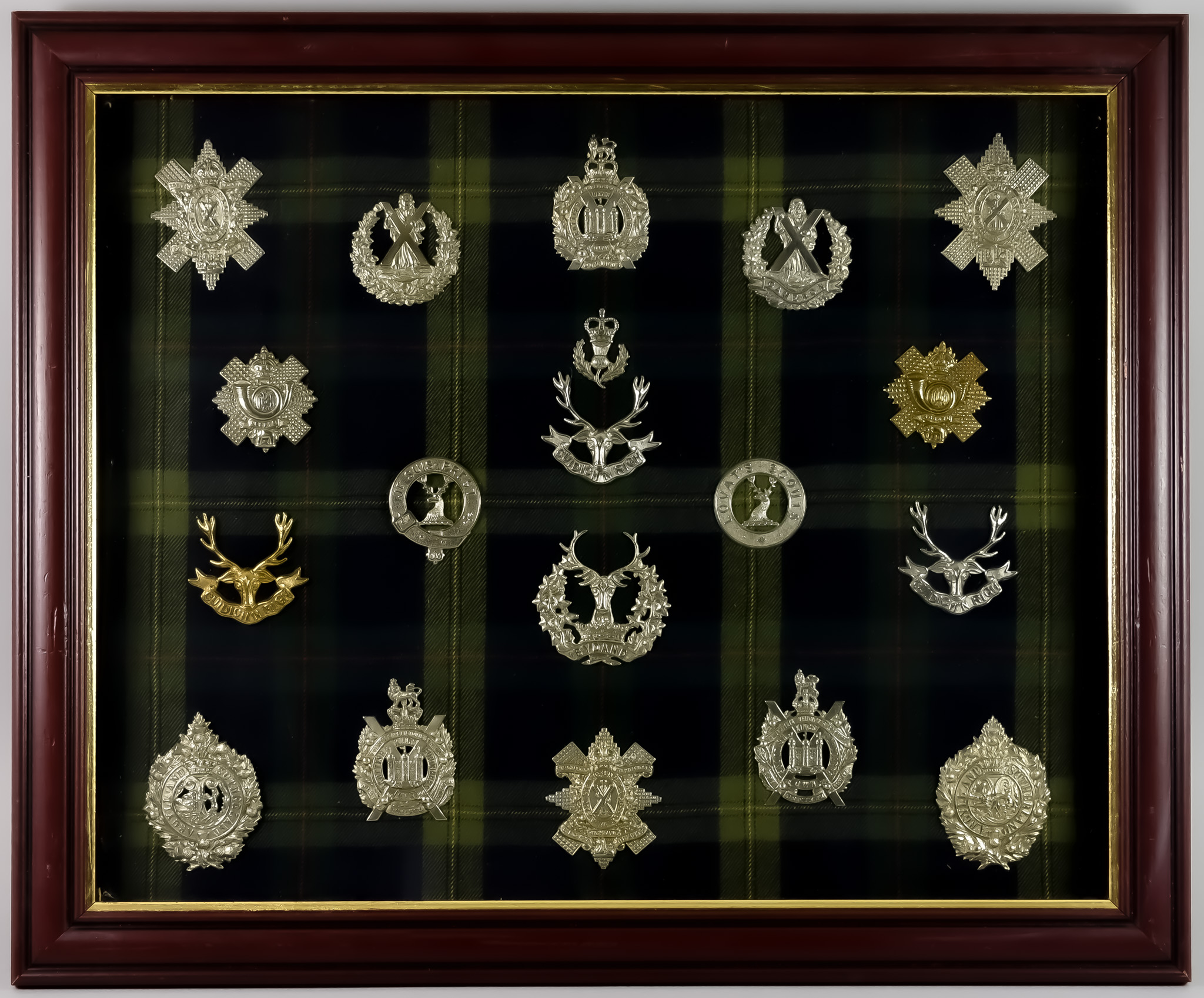 A Framed Collection of Scottish Regimental Cap Badges, on tartan background Note: Photographic