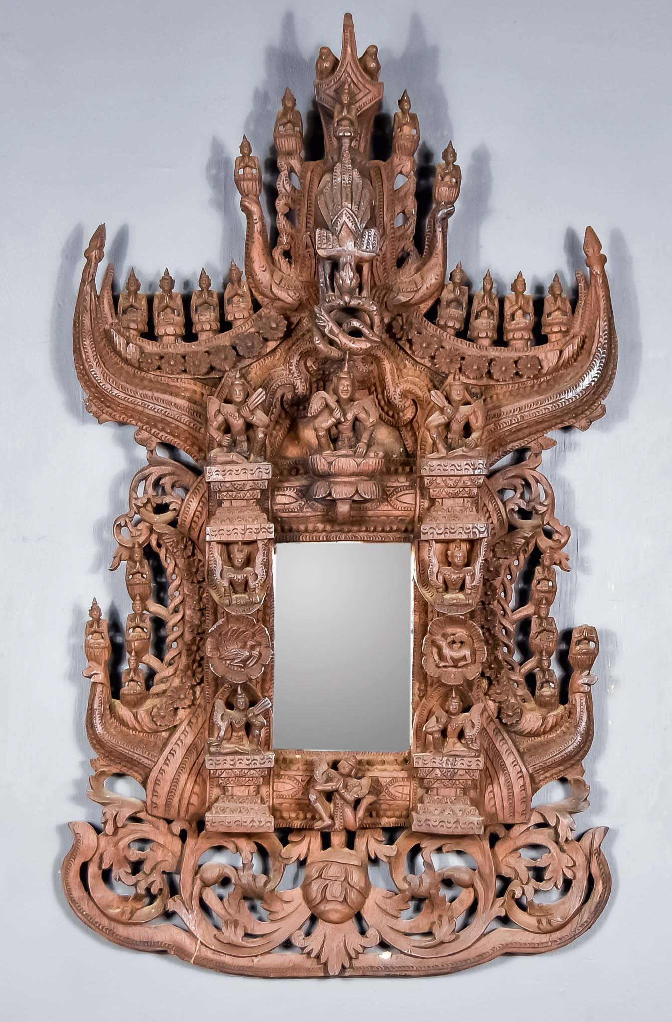 An Early 20th Century Indian Hardwood Wall Mirror, the frame carved with scrolling leaf floral