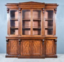 An Early Victorian Figured Mahogany Breakfront Bookcase, the upper part with architectural and