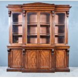 An Early Victorian Figured Mahogany Breakfront Bookcase, the upper part with architectural and