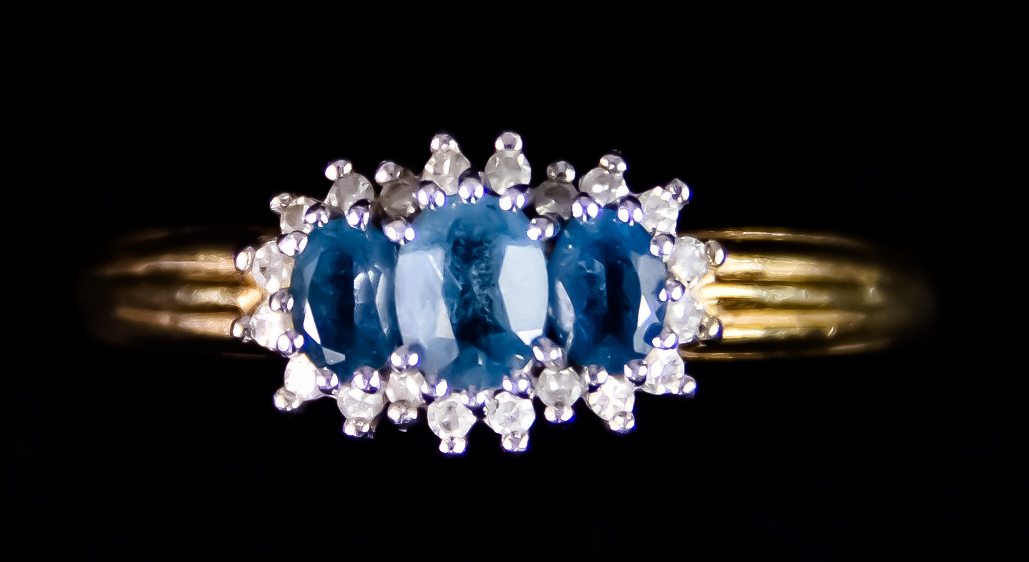 A 9t Gold Diamond and Blue Topaz Three Stone Ring, set with three faceted blue topaz stones,