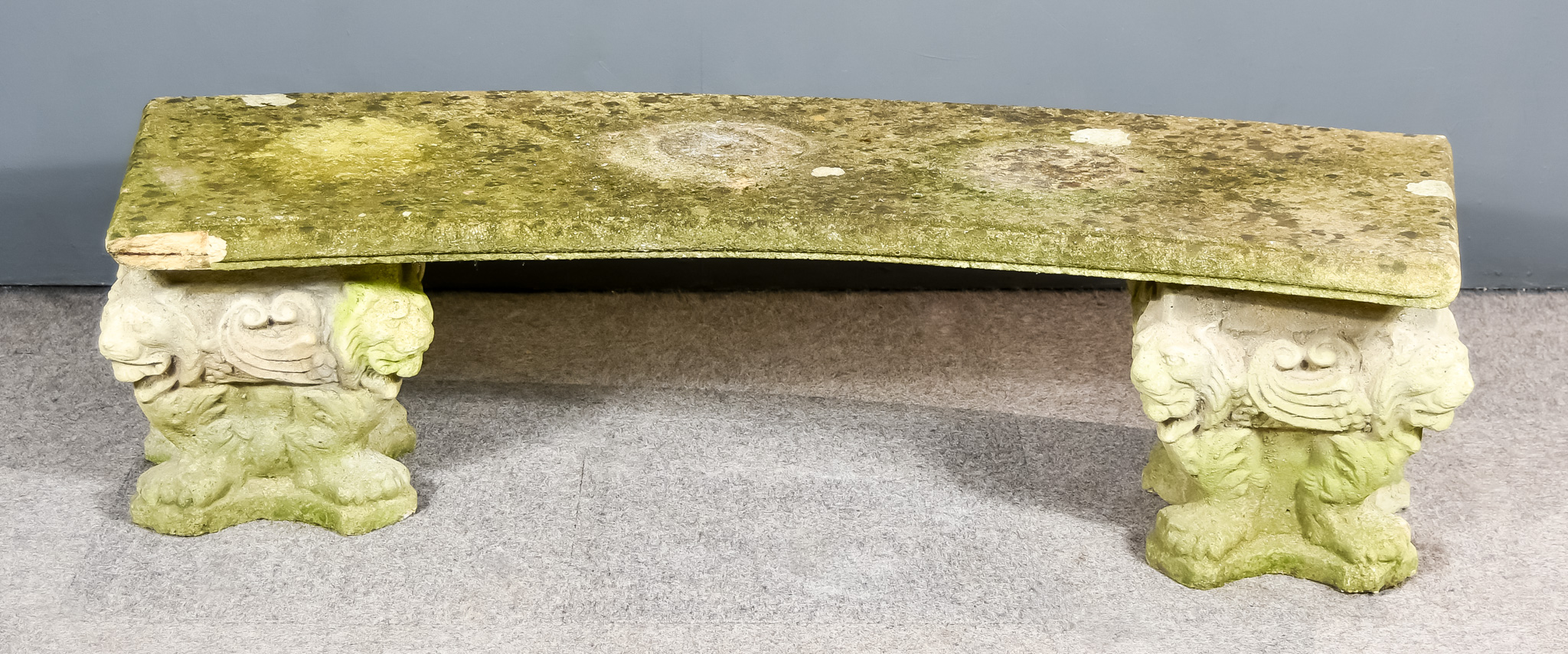 A Composition Stone Bench of Curved Form on Lion Moulded Bases, 16ins high x 54ins wide