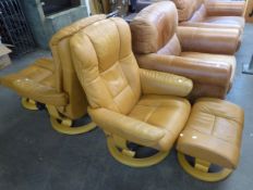 A PAIR OF STRESSLESS TAN LEATHER EASY ARMCHAIRS, WITH CIRCULAR WOODEN BASES, AND THE MATCHING FOOT-