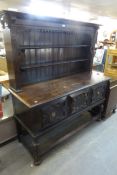 AN OAK DRESSER IN JACOBEAN STYLE, HAVING TWO CENTRAL DRAWERS, FLANKED BY TWO CUPBOARDS, WITH BRASS