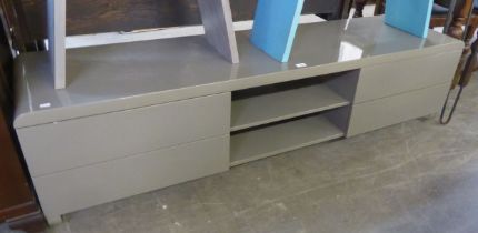A LONG LOW HIGH GLOSS GREY TV UNIT, HAVING OPEN CENTRAL SECTION, FLANKED BY TWO DRAWERS TO EACH SIDE