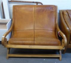 A TEAK FRAMED TWO SEATER PLANTATION STYLE SETTEE, COVERED IN BROWN LEATHER