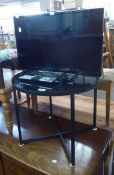 A SMALL FLAT SCREEN TELEVISION ON A CIRCULAR BLACK GLASS TOPPED TABLE